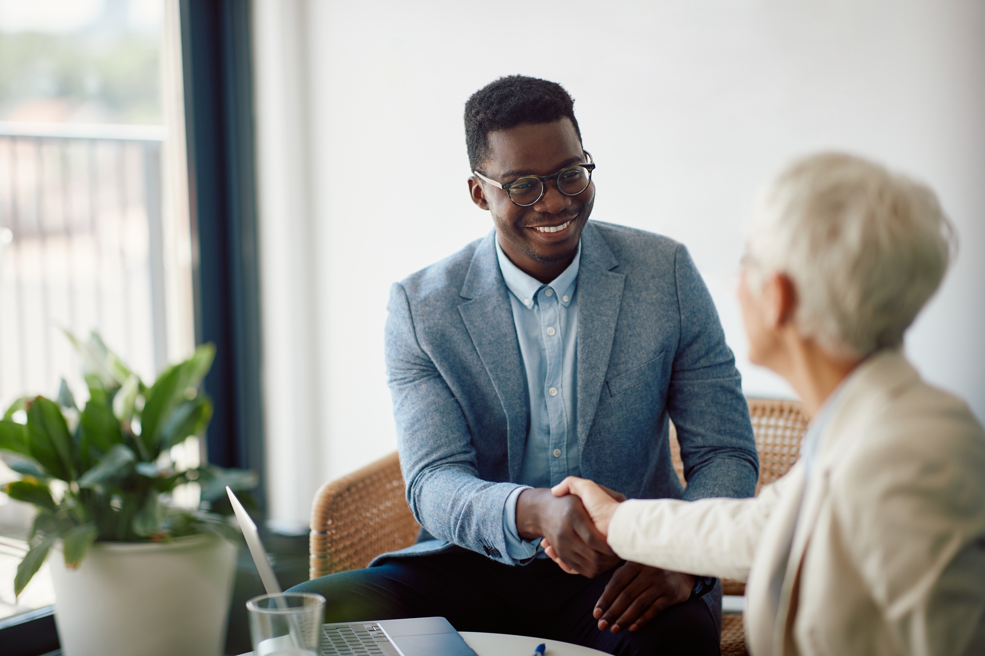 Happy black entrepreneur shaking hands with female colleague during business meeting in the office.